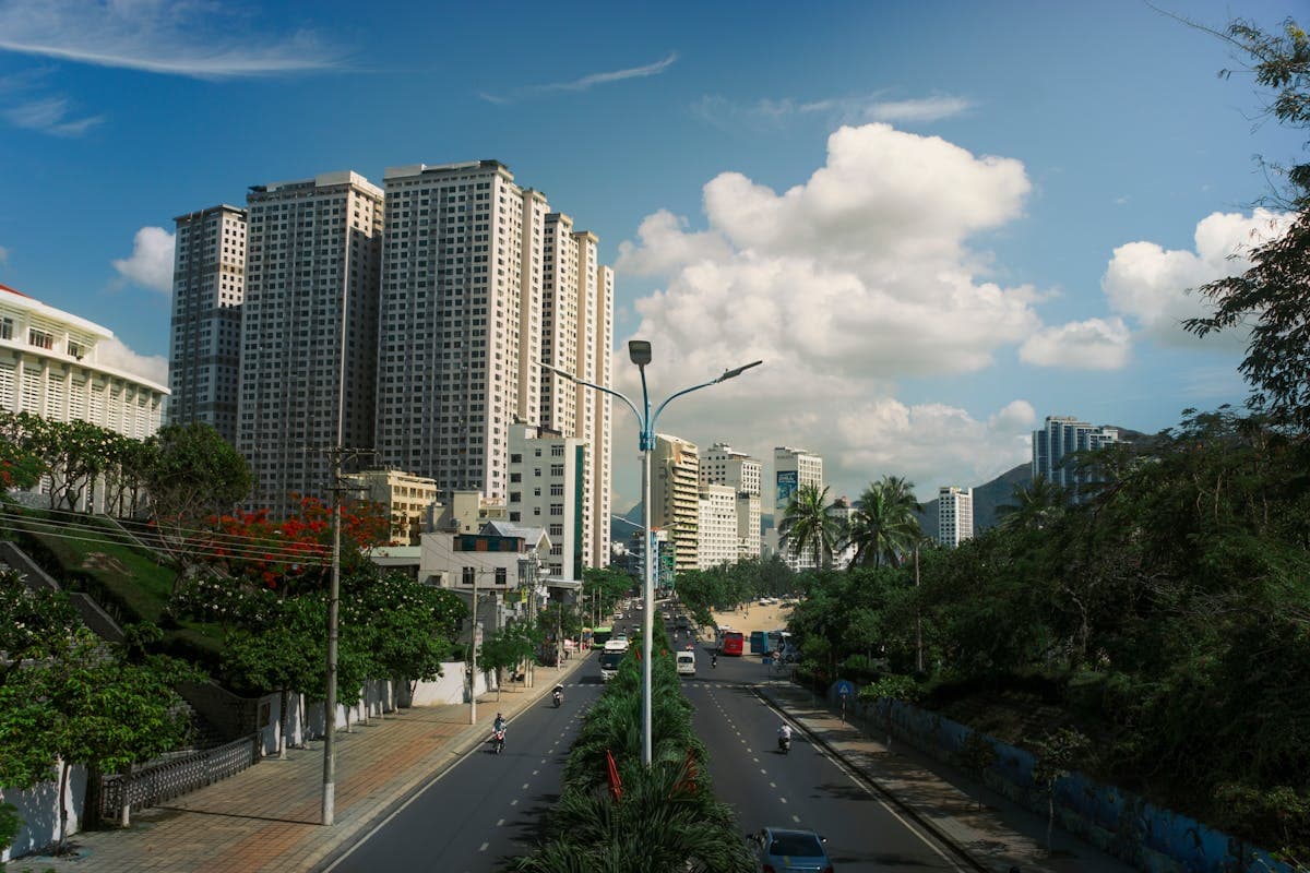 Высотные жилые дома Нячанга, дорога с мотоциклами и пальмы на фоне гор