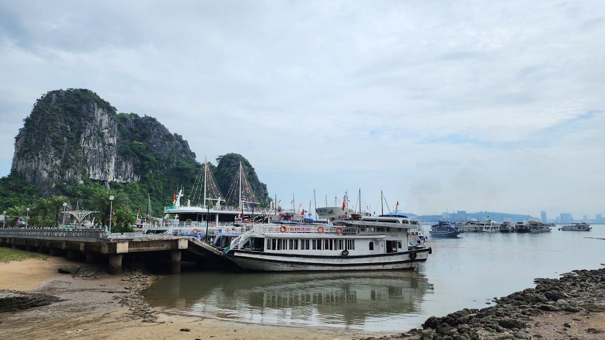 Круизные лодки у причала на фоне известняковых скал бухты Халонг