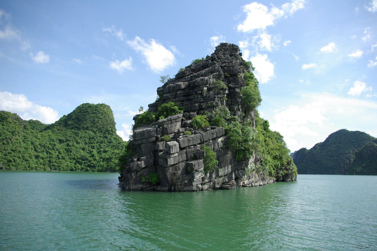 Известняковый карст бухты Халонг — скала с тропической зеленью в изумрудной воде