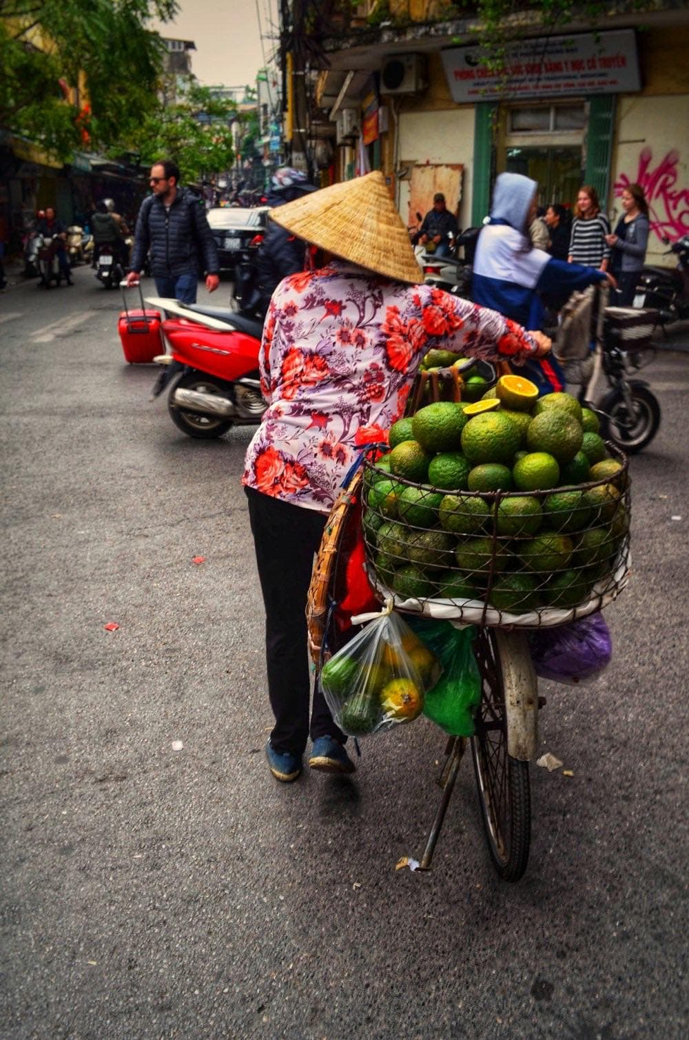 Уличная торговка с коромыслом и фруктами на улице Ханоя