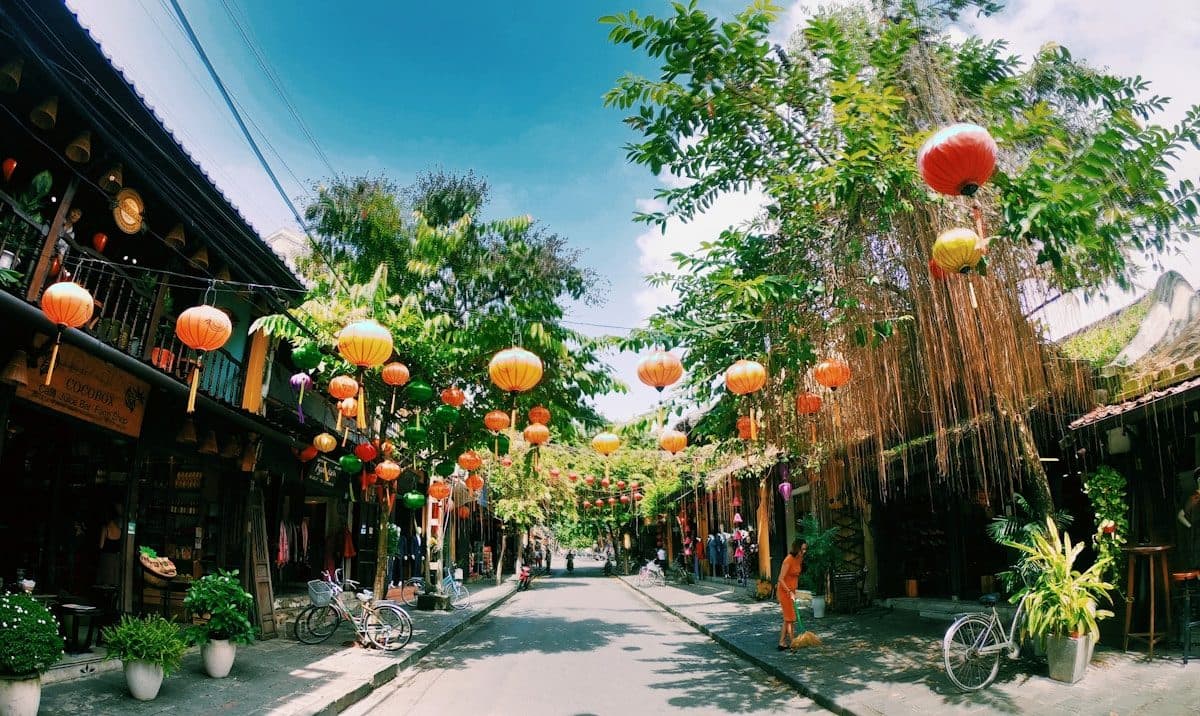 Жёлтые здания на улице Старого города Хойана с цветами и фонарями