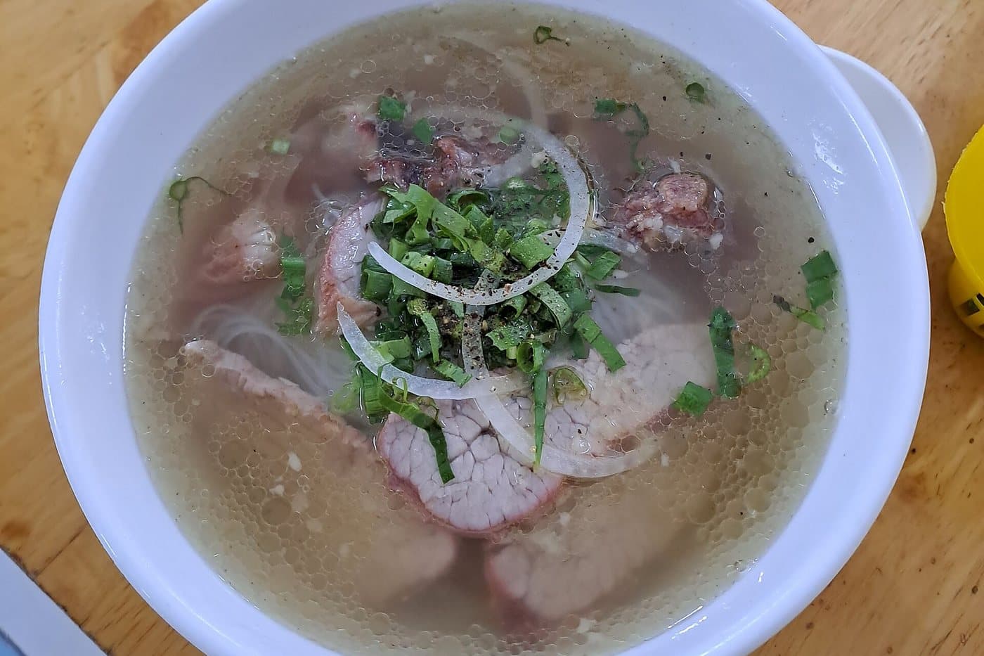 Миска лапши hủ tiếu Mỹ Tho с прозрачным бульоном, свининой, луком и зеленью в Митхо