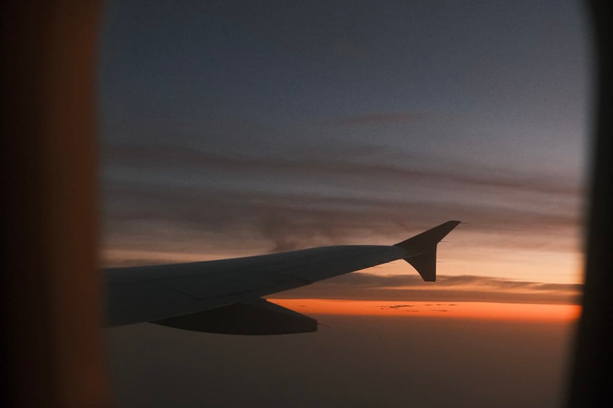 Вид из иллюминатора самолёта на крыло и закат во время перелёта