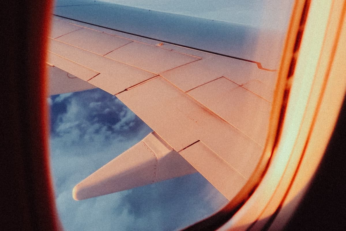 Пассажир с чемоданом в зале ожидания аэропорта наблюдает за взлётом самолёта