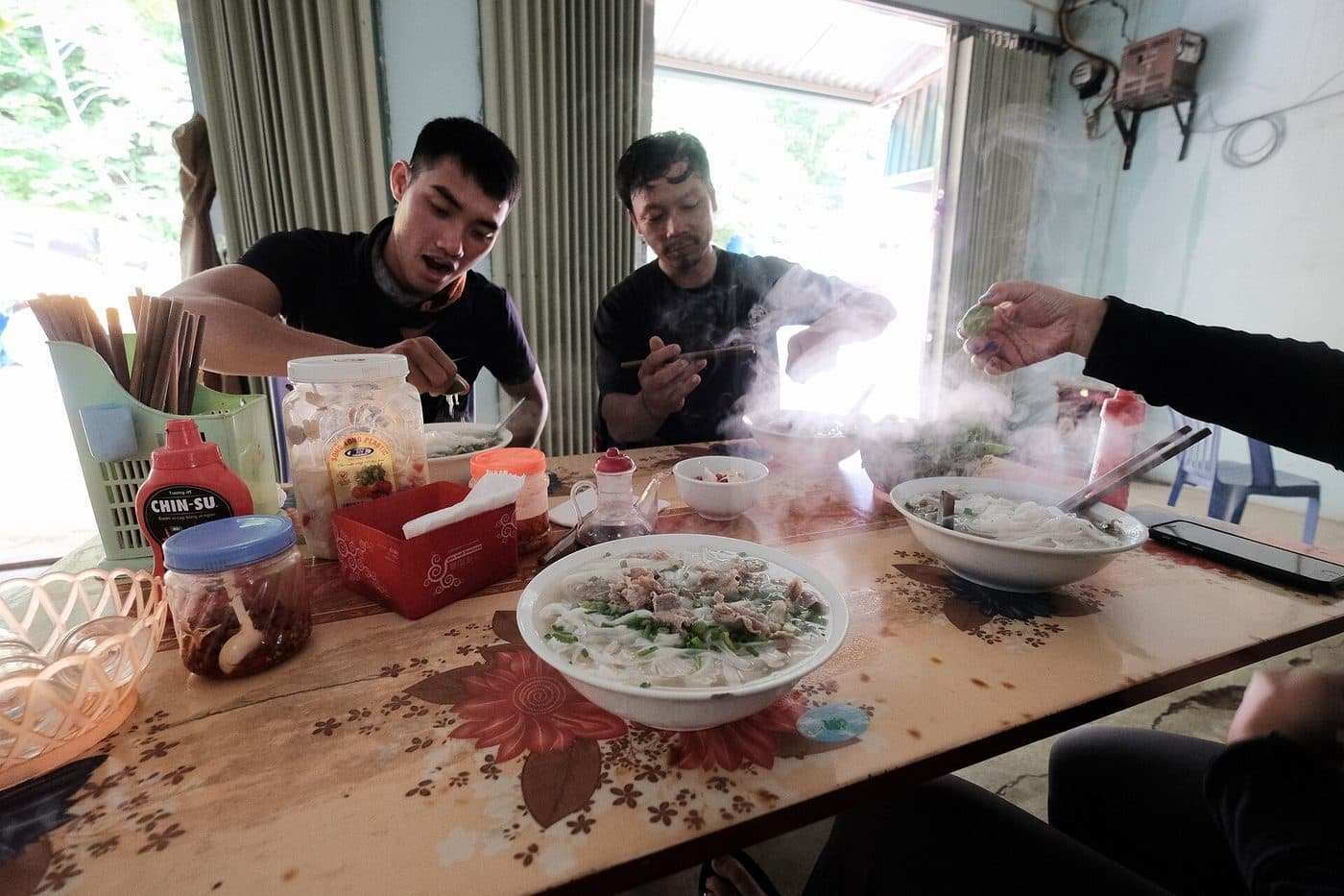 Миски дымящегося phở на столе в простой вьетнамской забегаловке