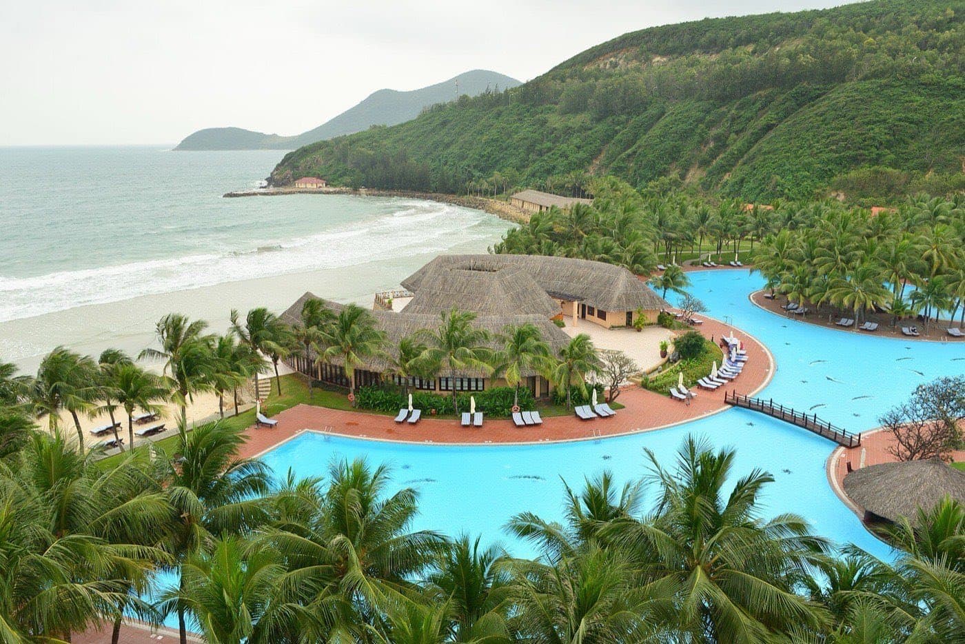 Pools of the Vinpearl resort by the beach on Hon Tre island, palms and hills