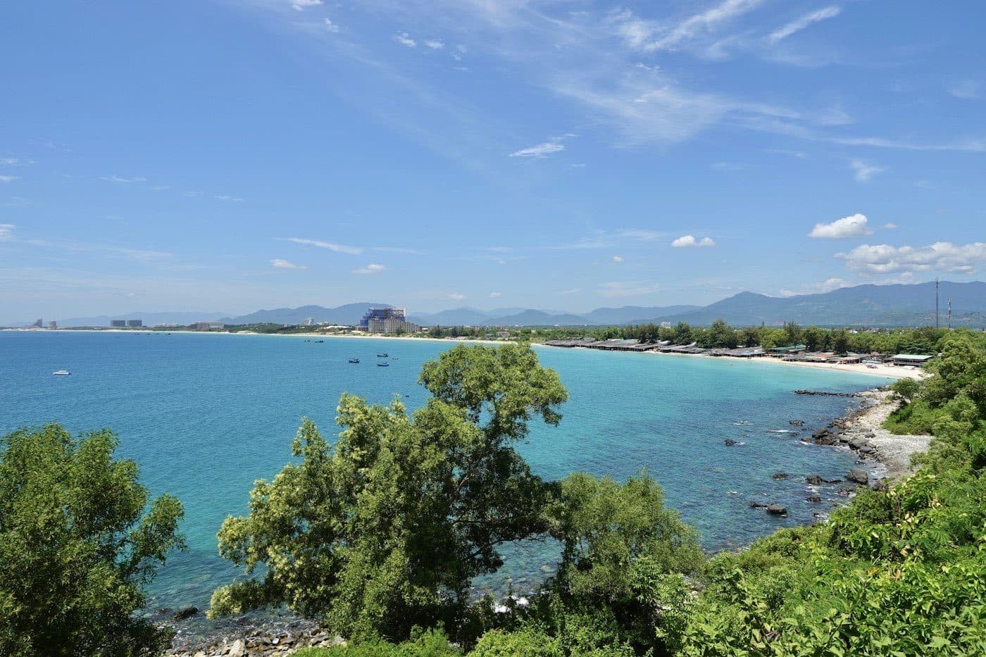 Turquoise bay and long beach in Cam Ranh with resort buildings in the distance
