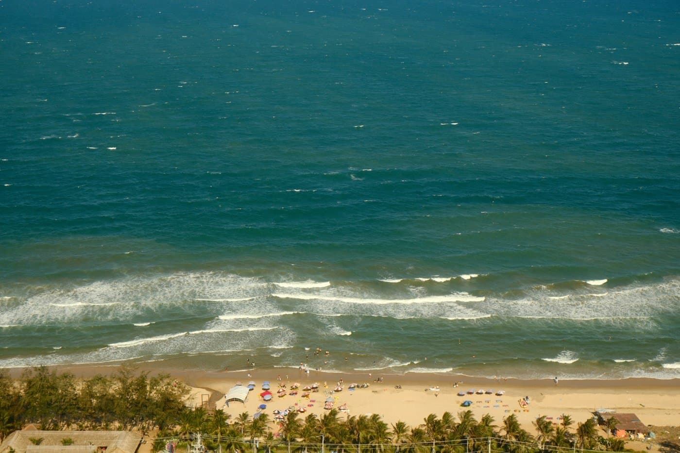 Mui Ne beach from above: umbrellas, palms and surf