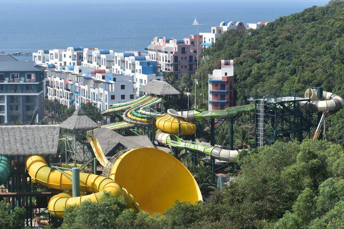 Water park slides on a green hillside by the sea