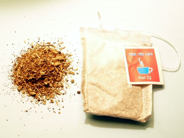 A 2 g bag of Vietnamese artichoke tea next to its emptied dry contents
