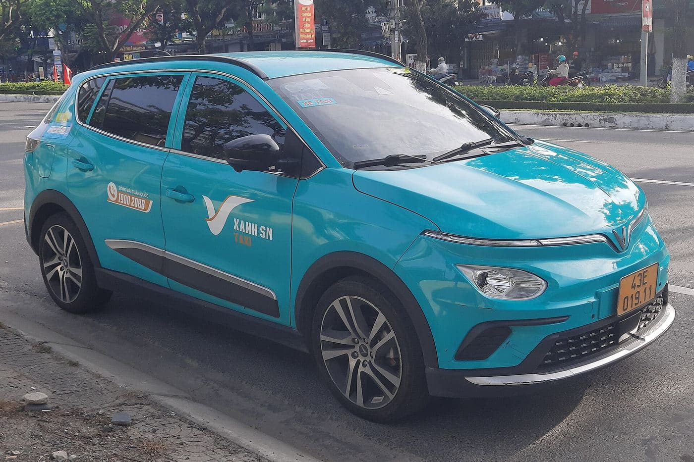 Бирюзовое электротакси Xanh SM, VinFast VF e34, у обочины улицы в Дананге