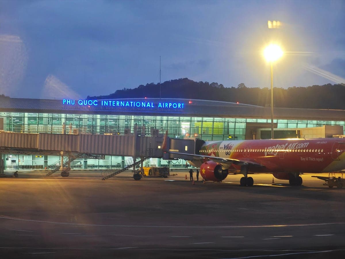 Терминал международного аэропорта Фукуок в сумерках, у телетрапа стоит Airbus VietJet Air
