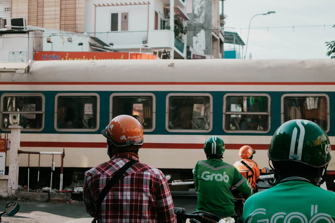 Поезд Тхонгнят на железнодорожном переезде в Хошимине и курьеры Grab в ожидании