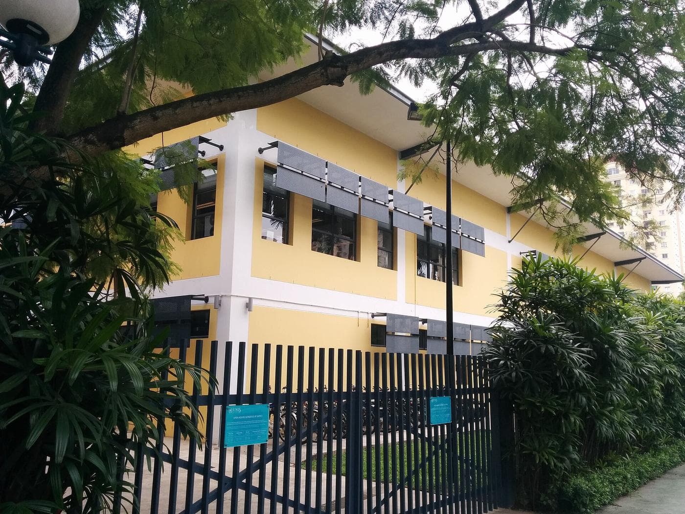 Жёлтый корпус UNIS Hanoi за металлической оградой в жилом комплексе Чипутра в Ханое