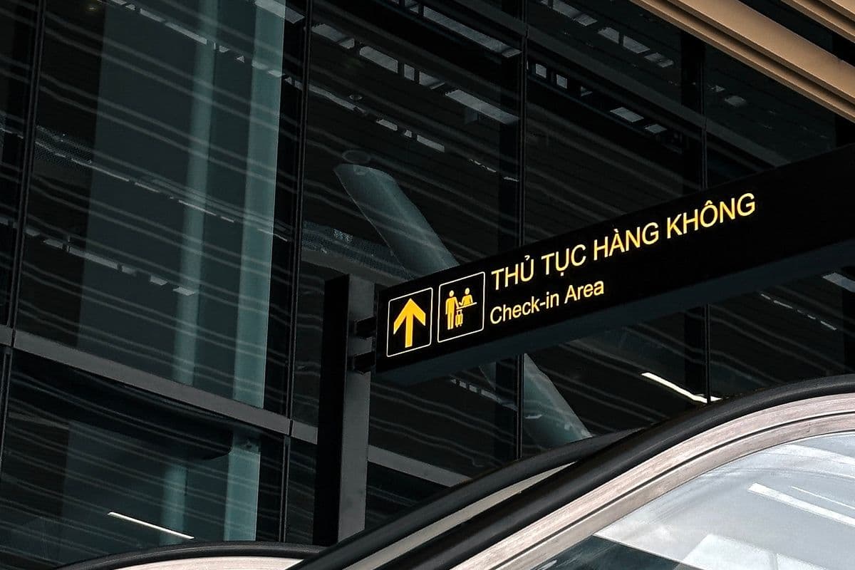 Указатель Thu tuc hang khong и Check-in Area в терминале вьетнамского аэропорта над эскалатором