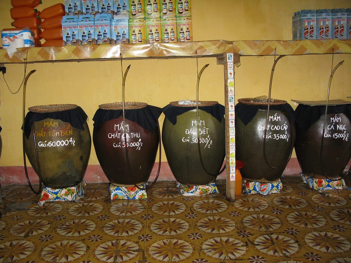 Clay jars of fish sauce and boxed bottles in a shop at the Cat Ba market