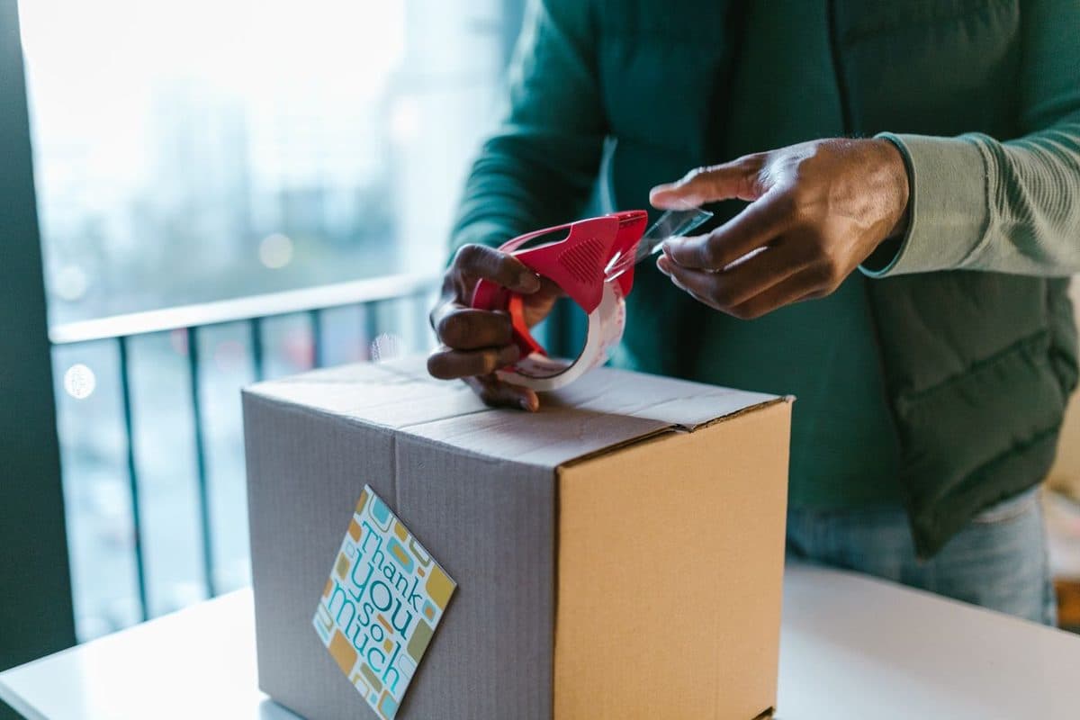 Packing a parcel: sealing a cardboard box with tape from a dispenser