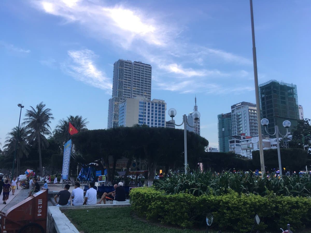 Nha Trang high-rises behind a seafront park, one tower still wrapped in construction netting