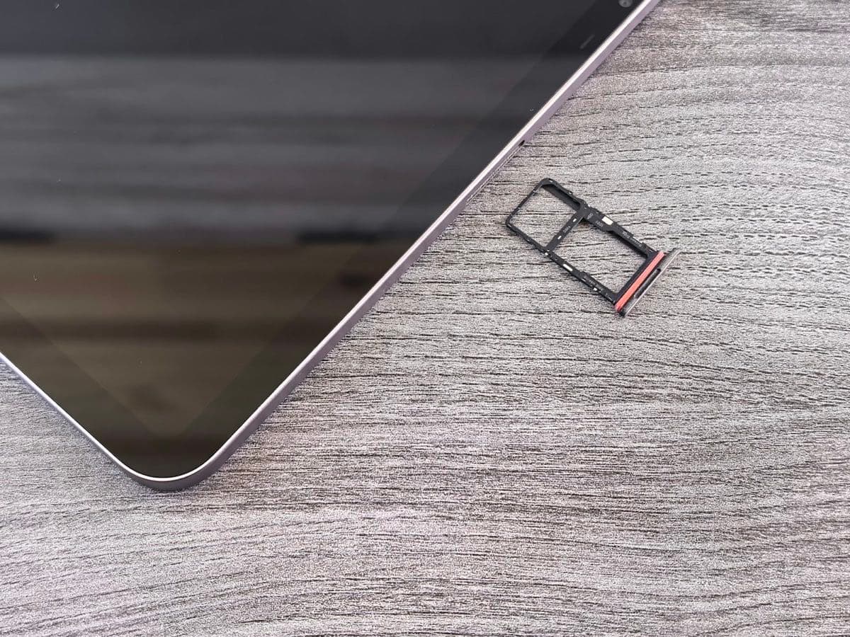 A removed SIM card tray lying on a table next to a device