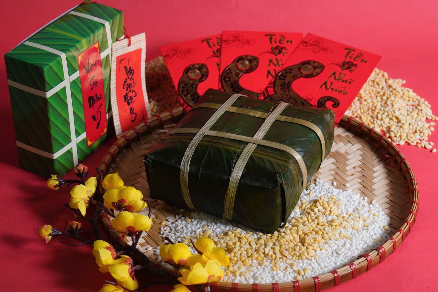 Tet set with banh chung in banana leaf, red envelopes and a yellow apricot branch