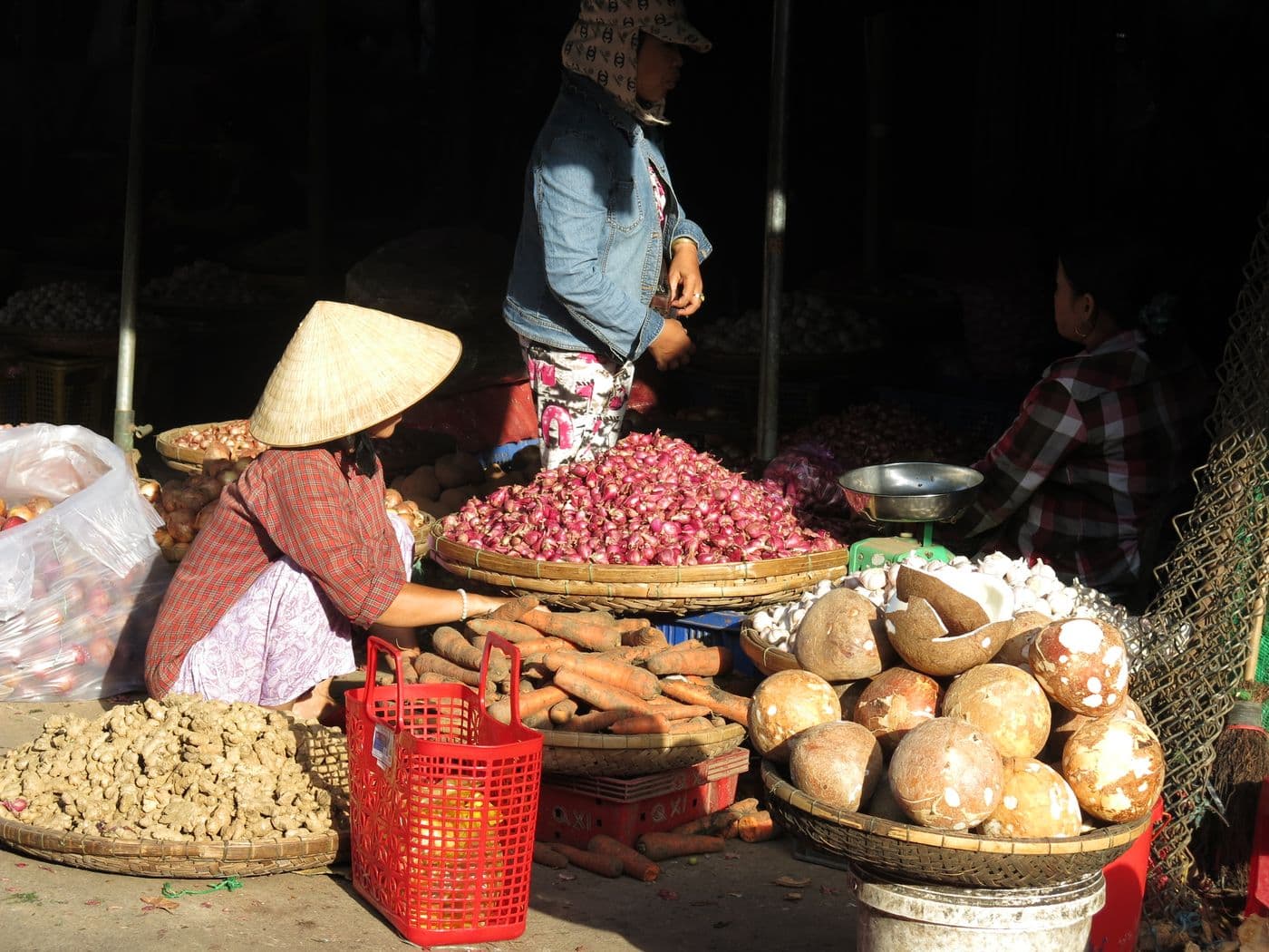 Early morning market in Vietnam with a vendor in a conical hat and baskets of produce