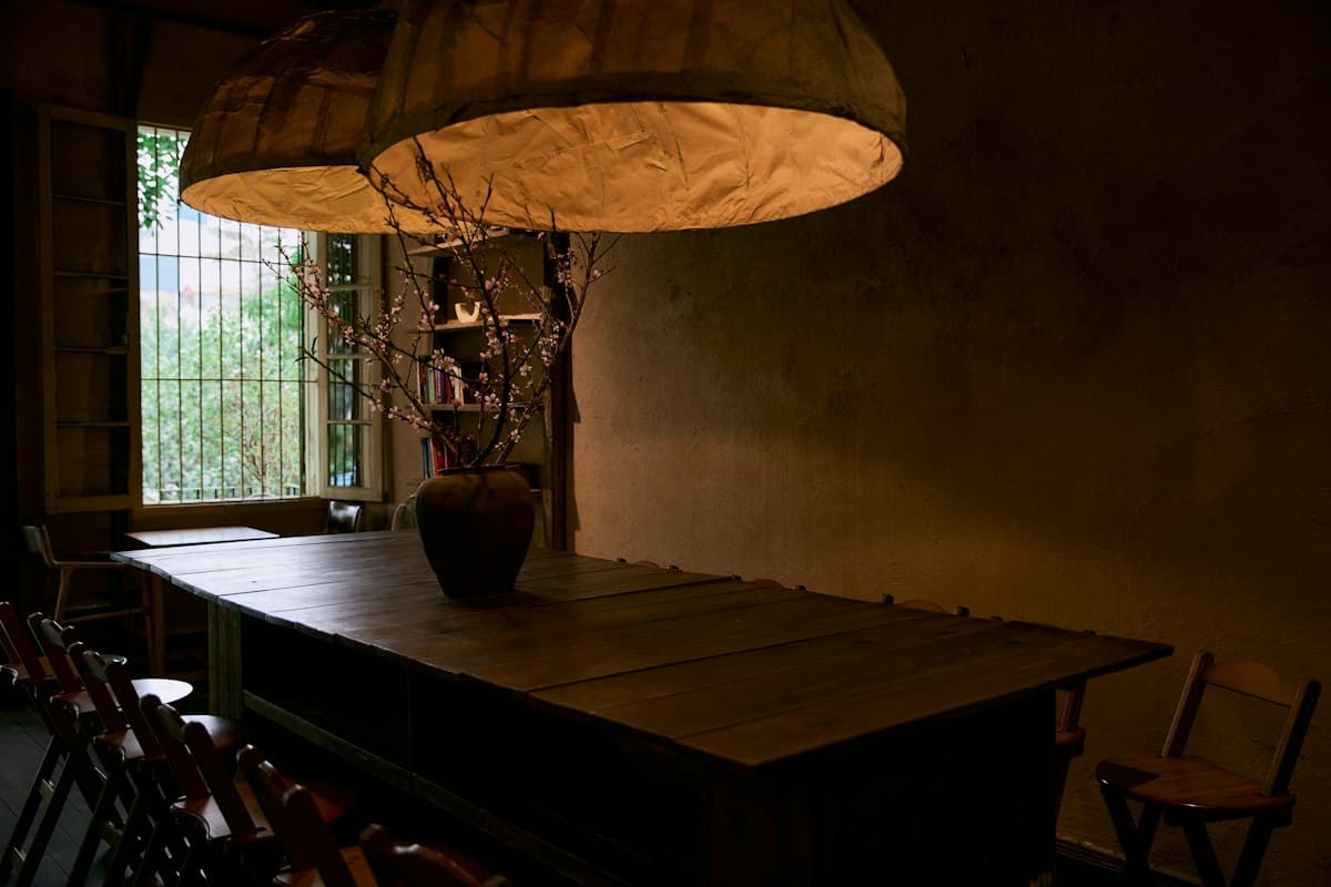Long wooden communal table under paper lampshades in a Vietnamese coffee shop