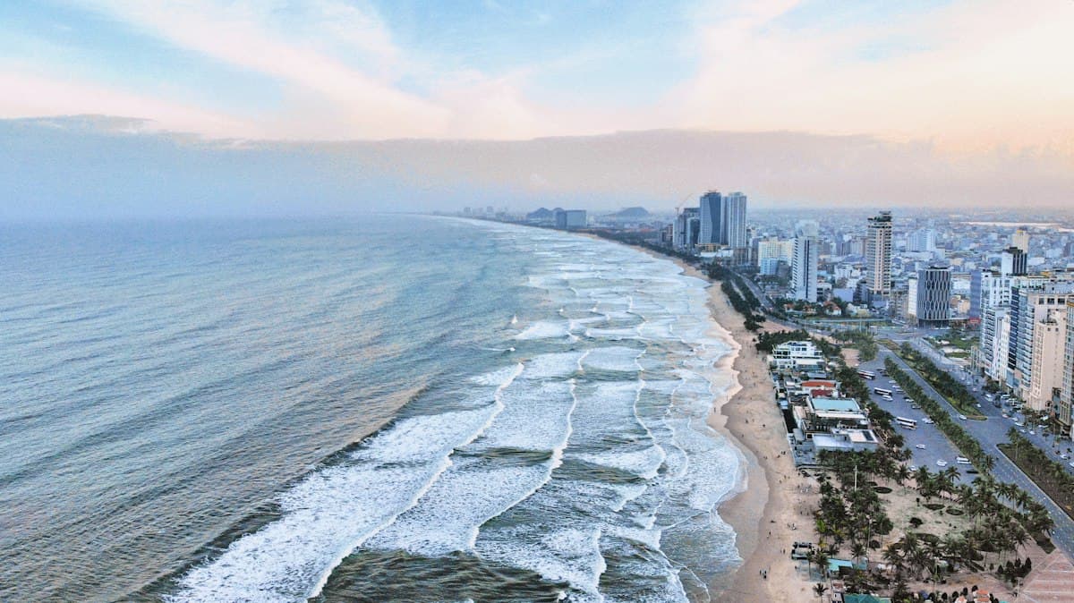 Aerial view of the Da Nang coastline with a long beach and city towers