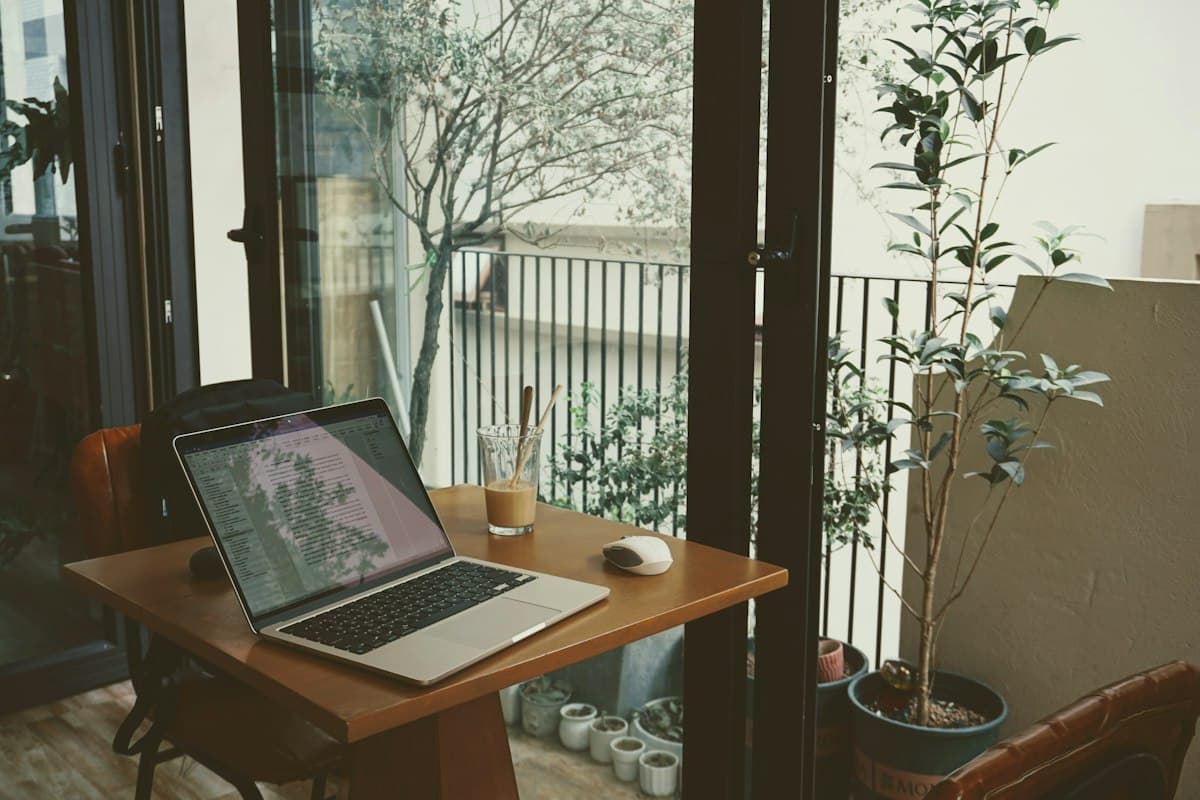 Laptop and Vietnamese iced coffee on a wooden table by a cafe window