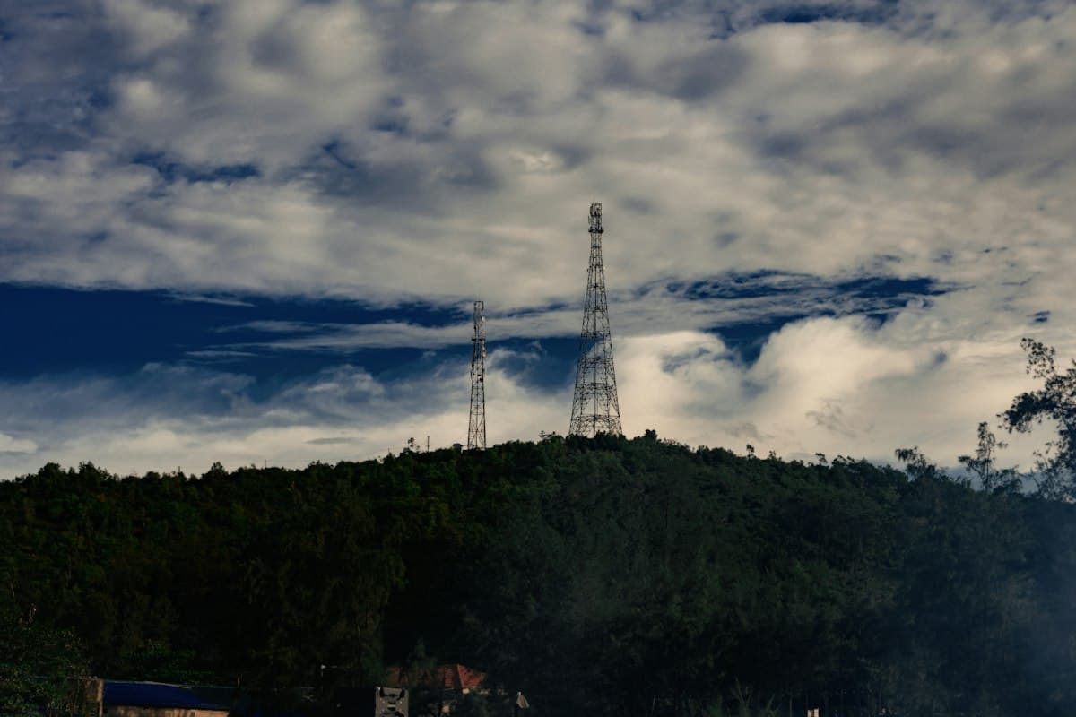 Two mobile network towers on a forested hill in the Vietnamese highlands
