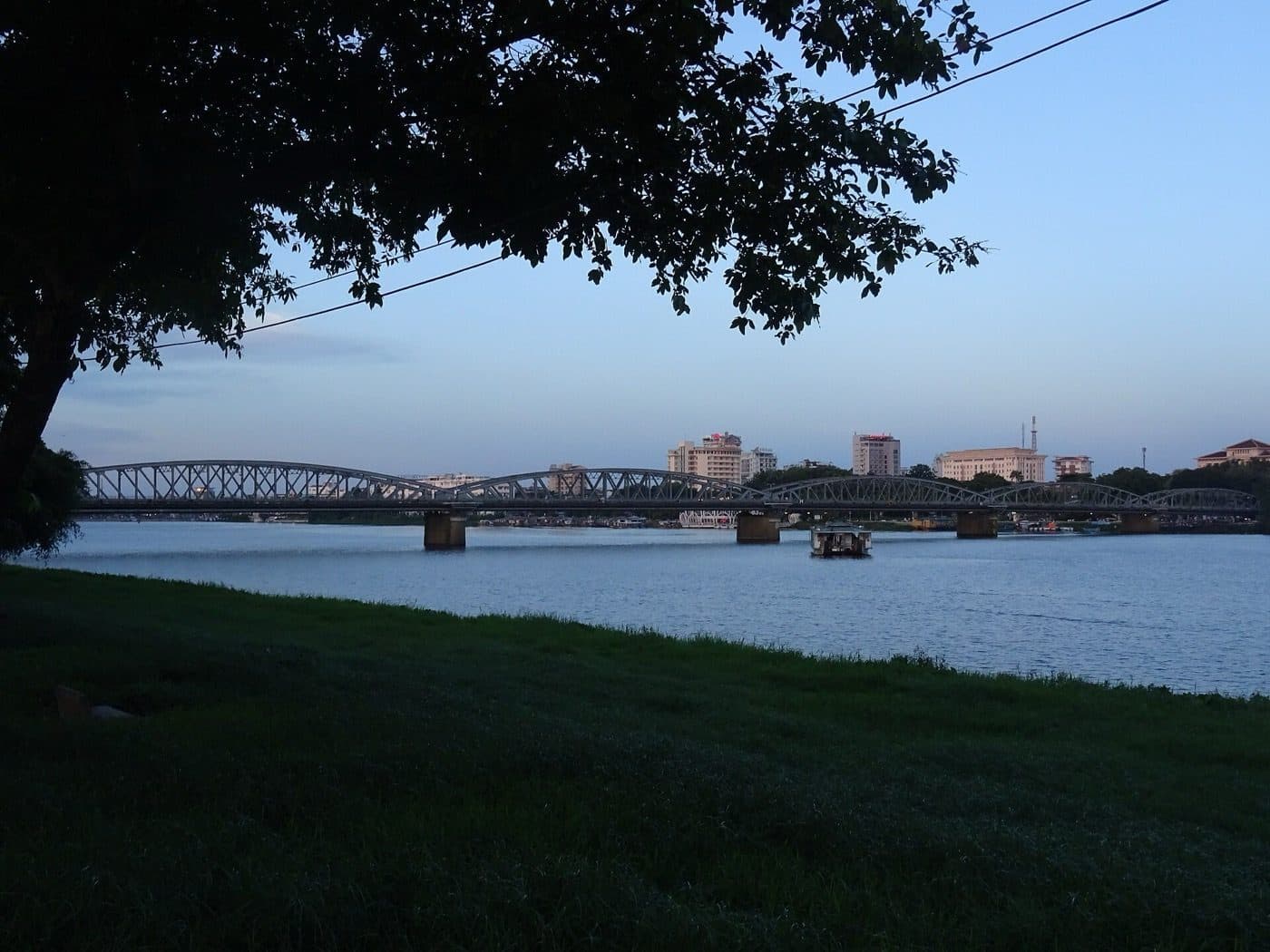 Мост Чыонгтьен через Парфюмерную реку в Хюэ на закате, у берега пришвартованы лодки
