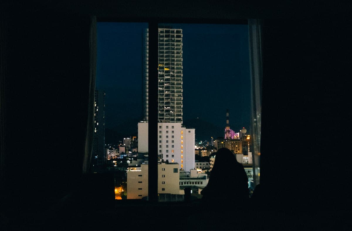 Nha Trang at night from a high-rise window, a silhouette against the towers