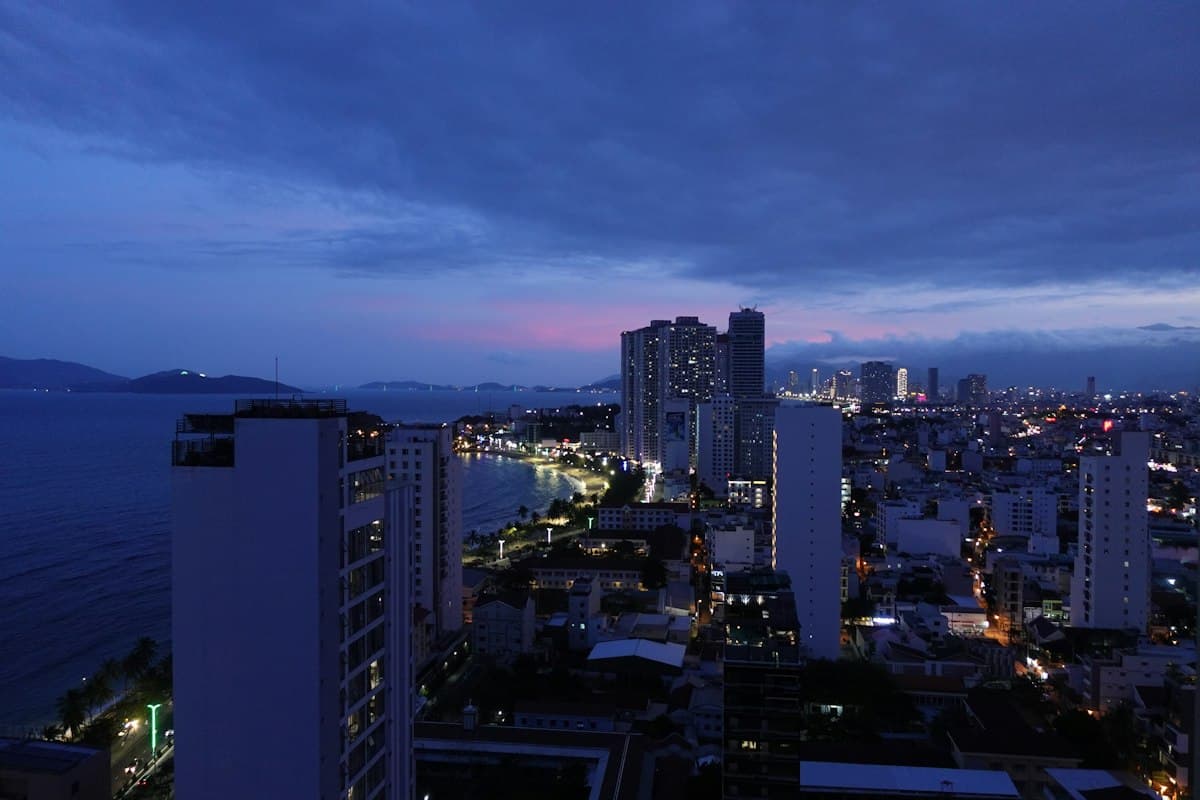 Nha Trang at dusk from above: towers along the curve of the beach and seafront lights