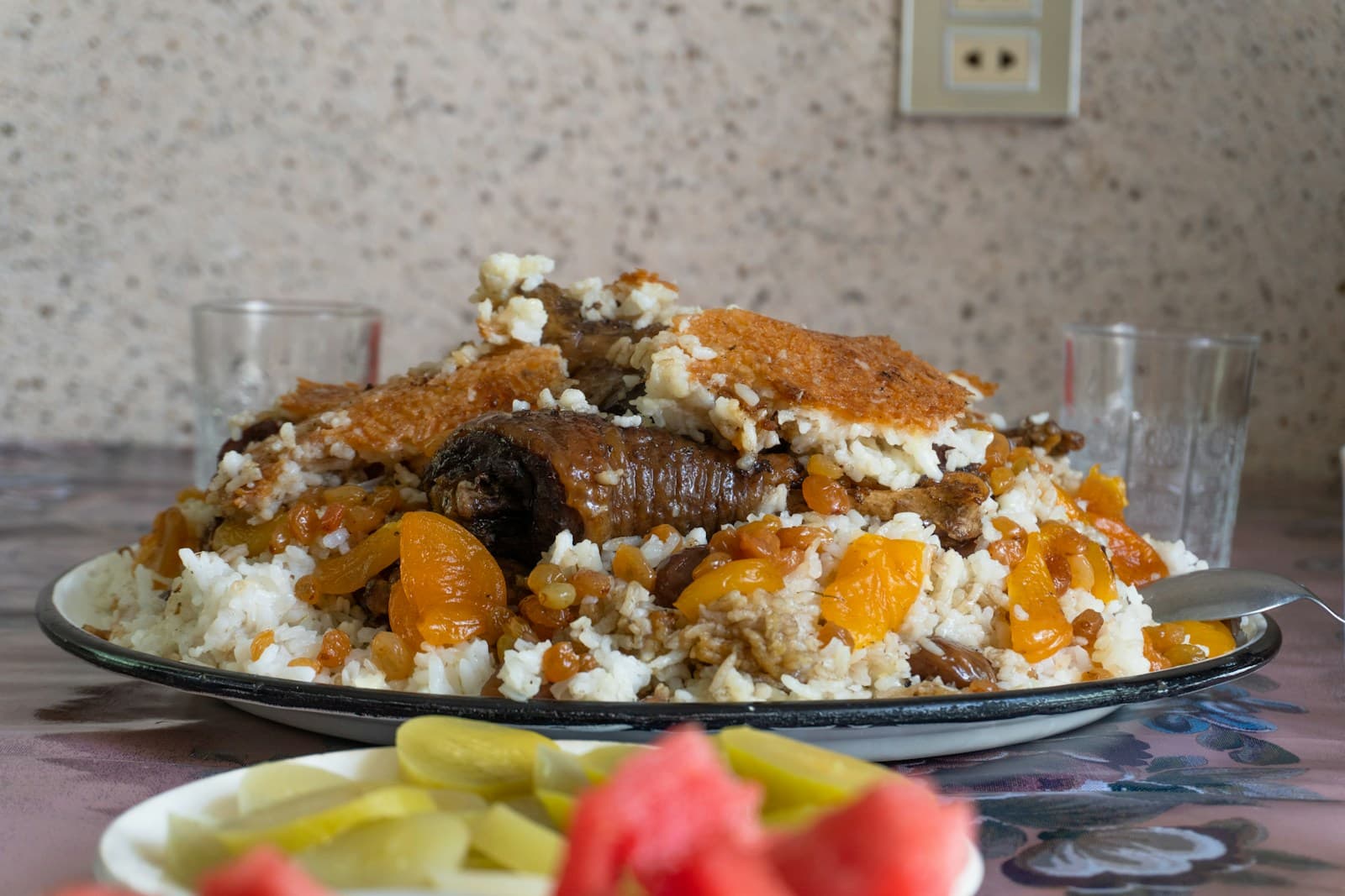 Большая тарелка узбекского плова с курагой, изюмом и мясом на столе в кафе