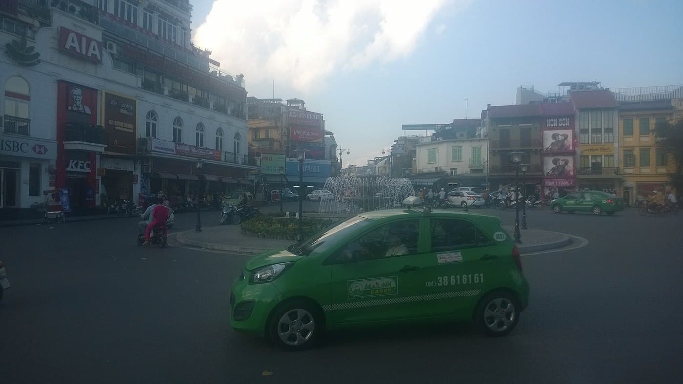 Зелёное такси Mai Linh с номером диспетчера на двери на площади у озера Хоанкьем в Ханое