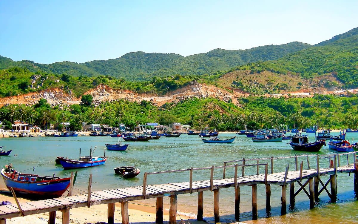 Wooden jetty and blue fishing boats by the village in Vinh Hy Bay