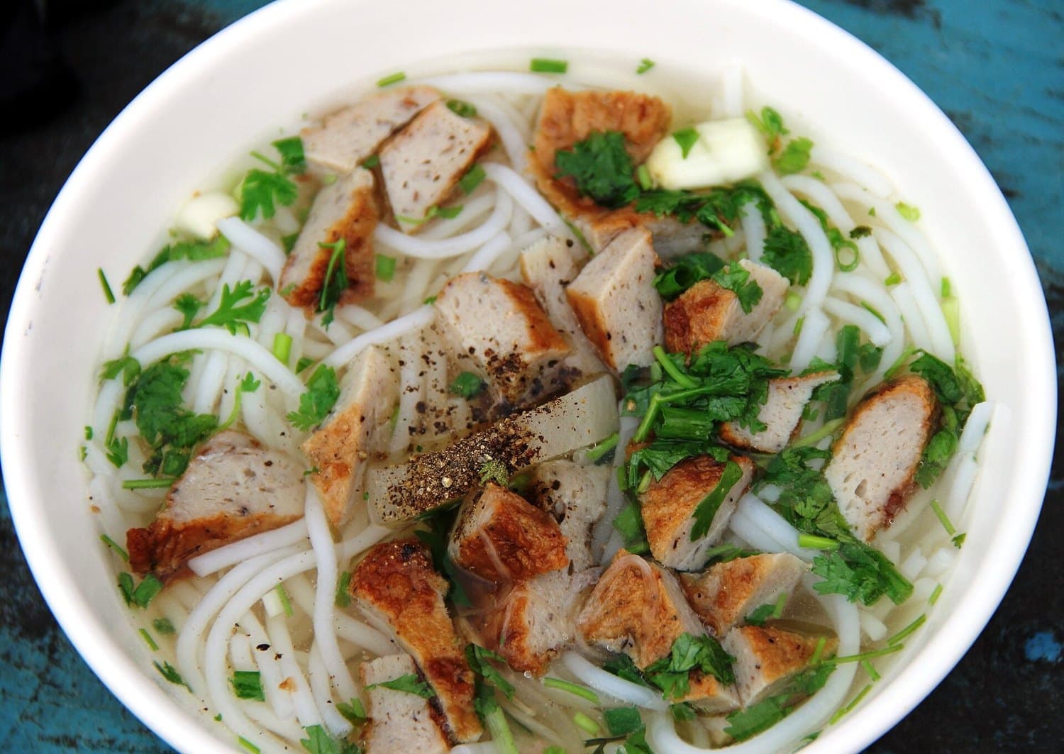Миска bún chả cá: рисовая лапша, ломтики рыбных котлет, кориандр и прозрачный бульон