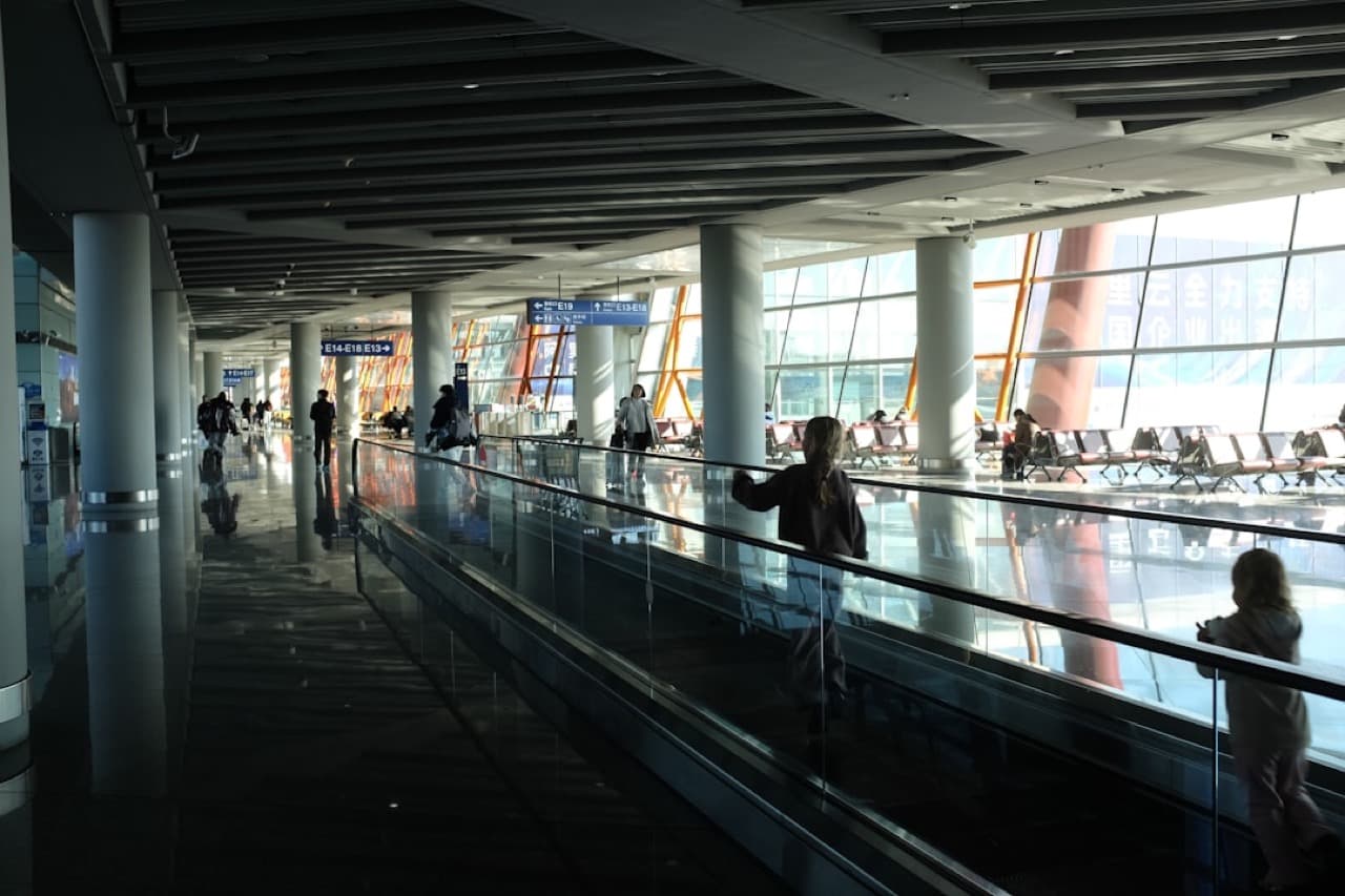 Пассажир в зале ожидания аэропорта смотрит на взлетающий самолёт