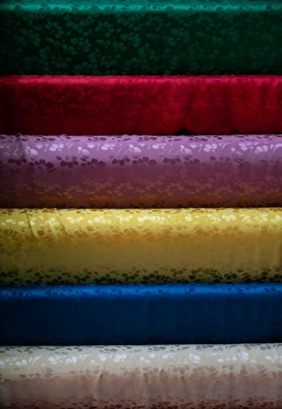Рулоны шёлковой ткани ярких цветов в мастерской Хойана