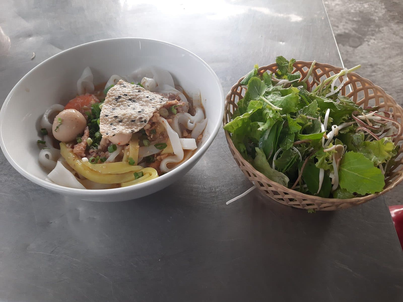 Миска ми куанг с жёлтой и белой рисовой лапшой, перепелиным яйцом, кунжутным крекером и корзинкой зелени