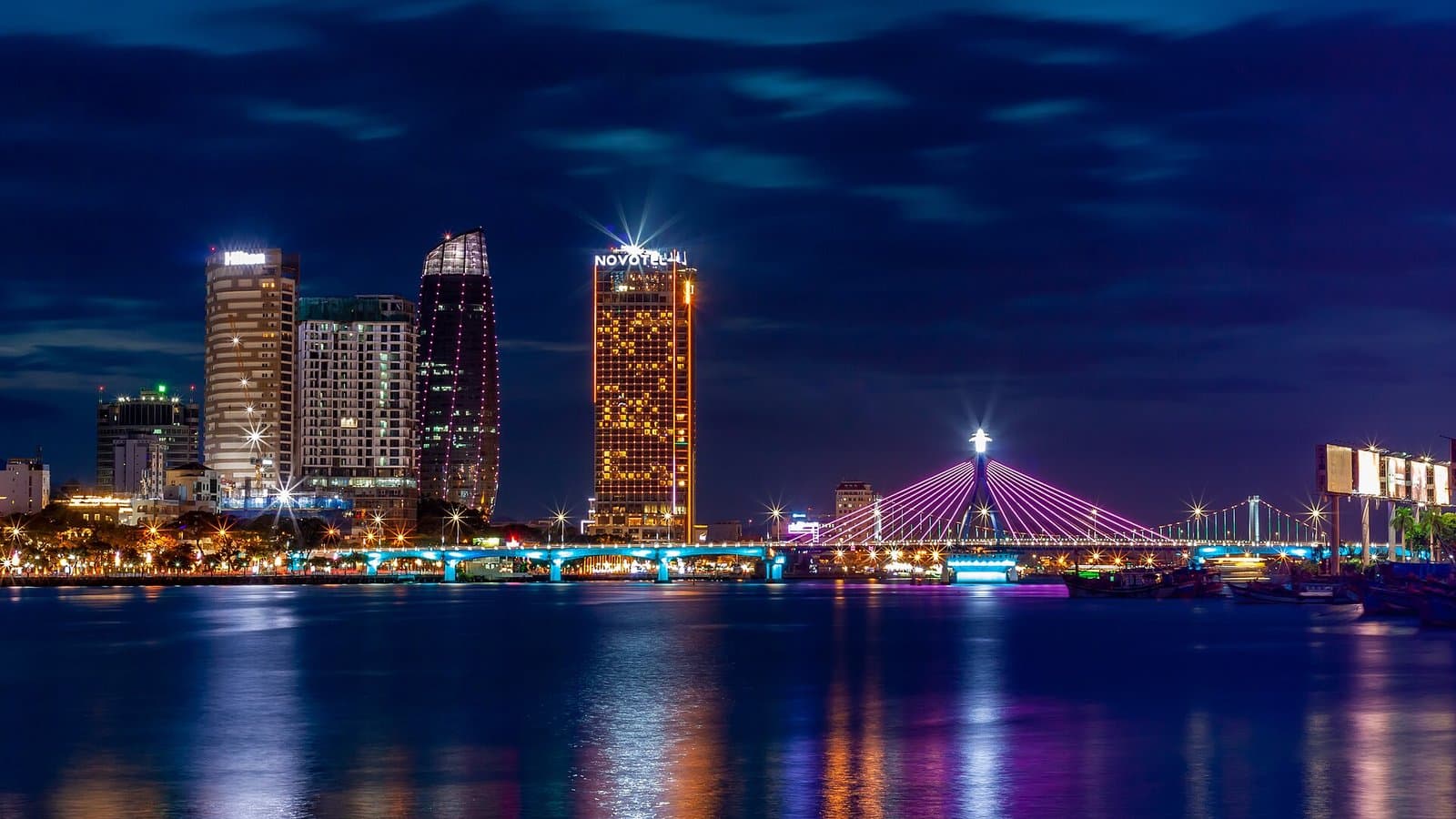 The lit Song Han bridge and riverside towers on the Han River in Da Nang