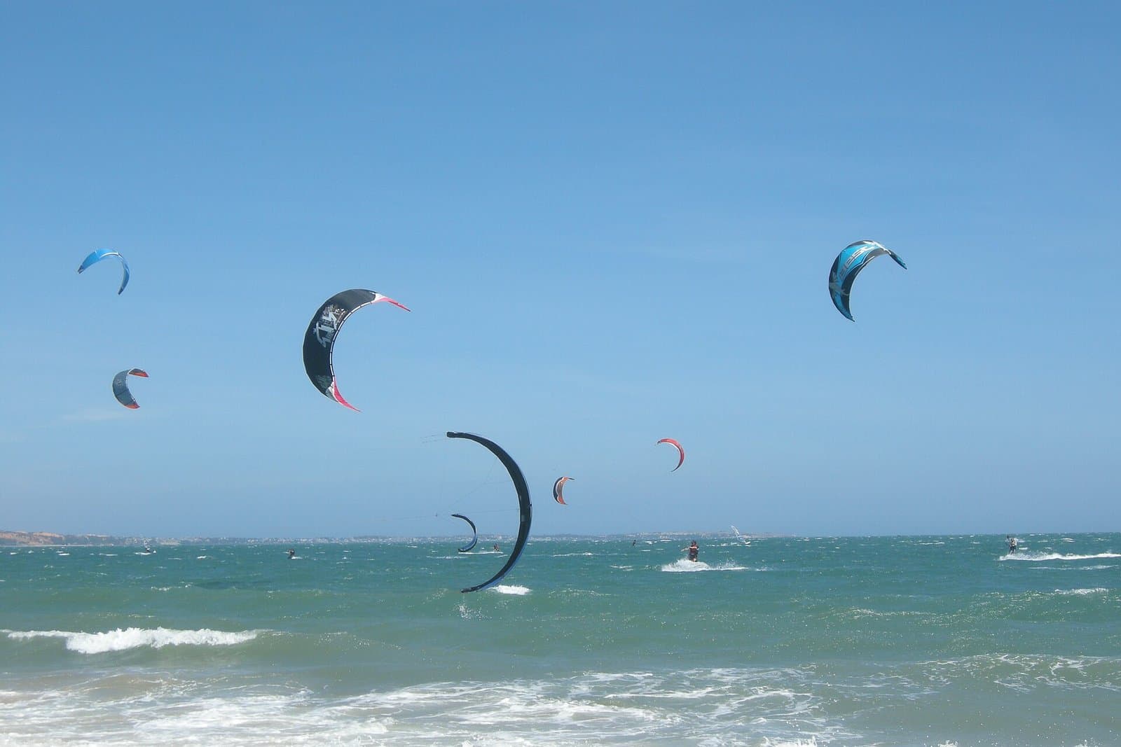Kites and kitesurfers over the water at Ham Tien beach in Mui Ne