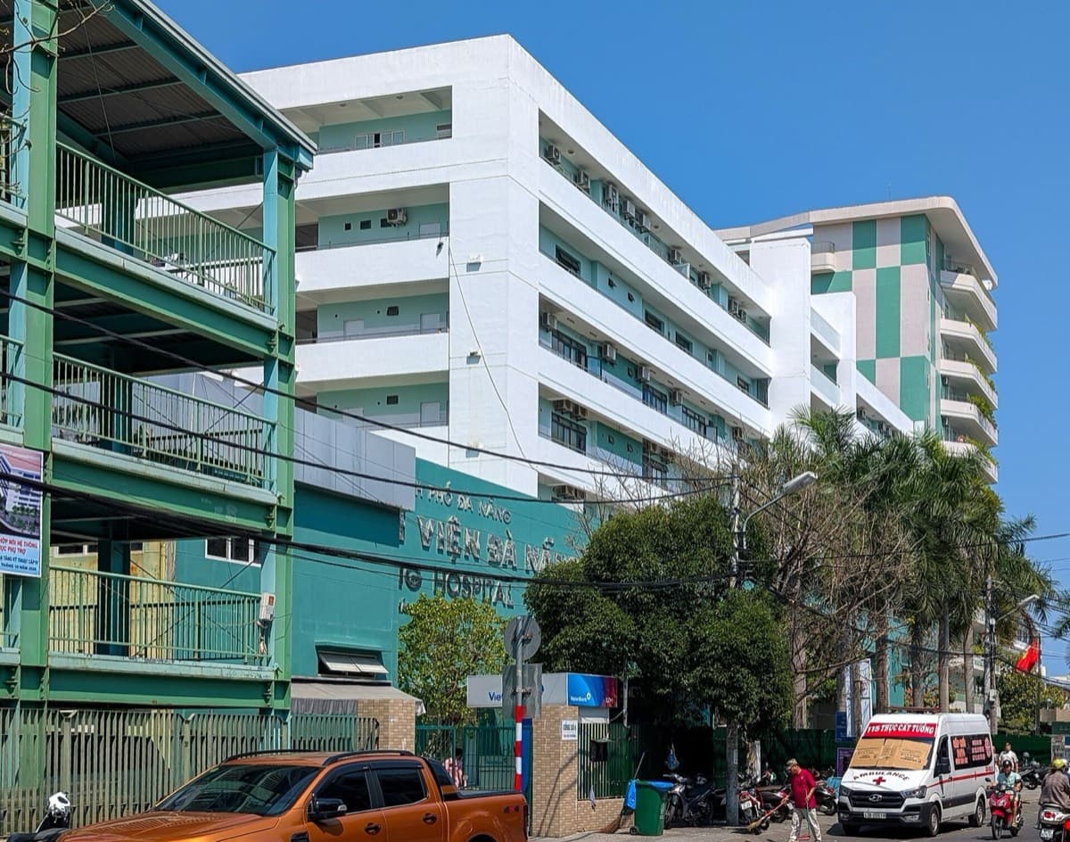 A hospital in Da Nang with an ambulance at the gate and motorbike traffic outside