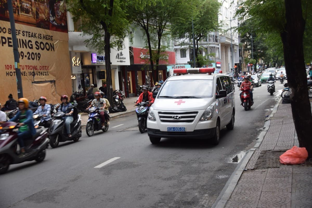 An ambulance moving through motorbike traffic on a Ho Chi Minh City street