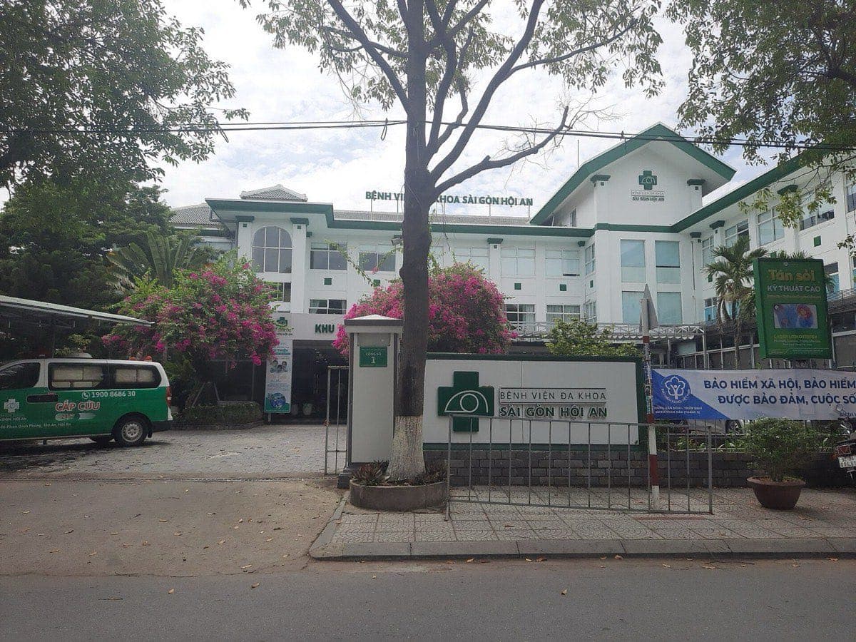 A Vietnamese hospital in Hoi An with a health insurance banner at the gate