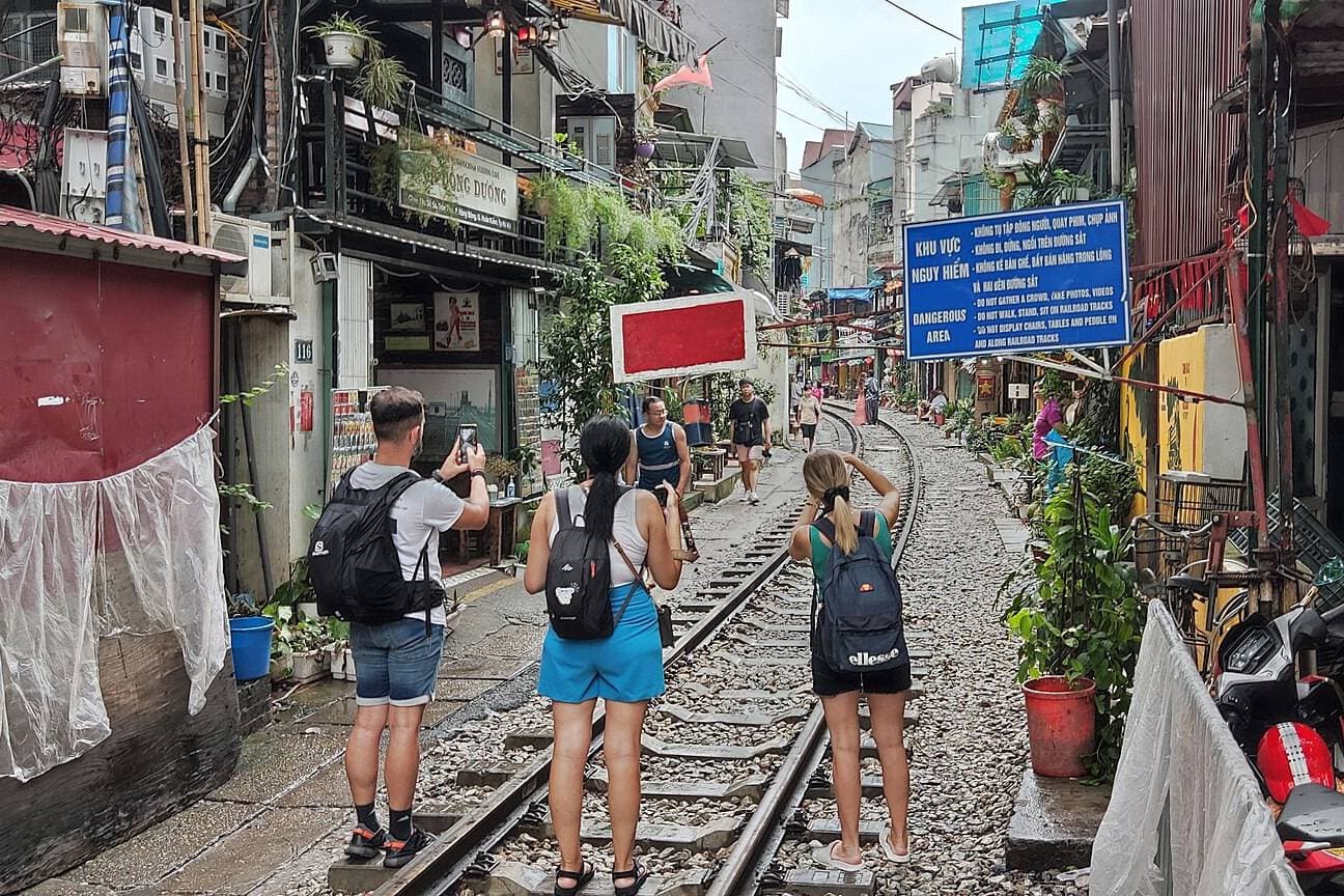 Tourists filming on their phones on Hanoi's Train Street next to a no-filming sign