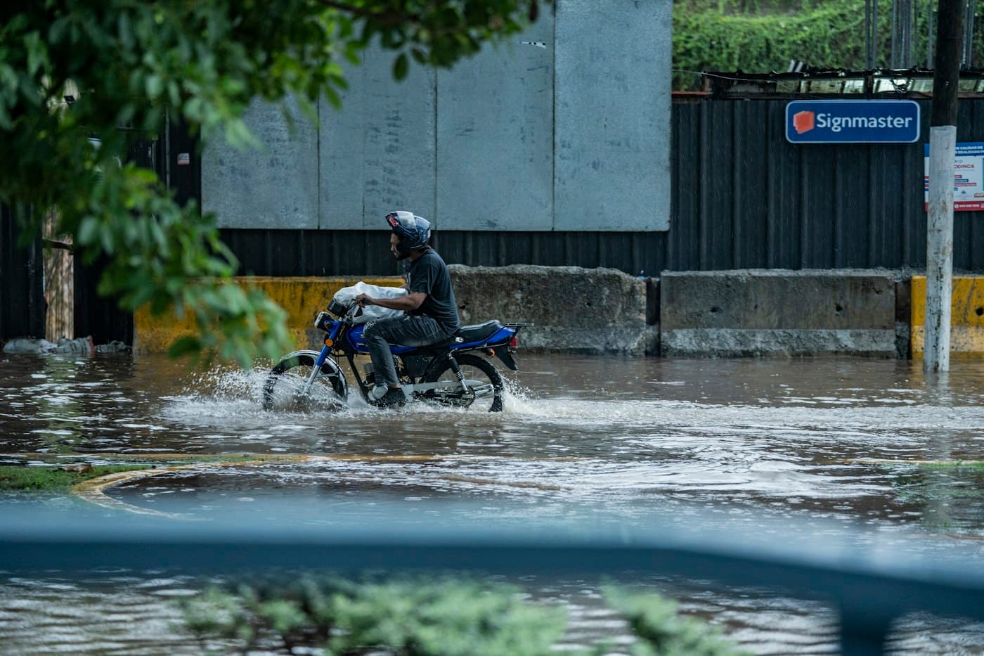 Motorcyclist in a helmet riding through a flooded city street