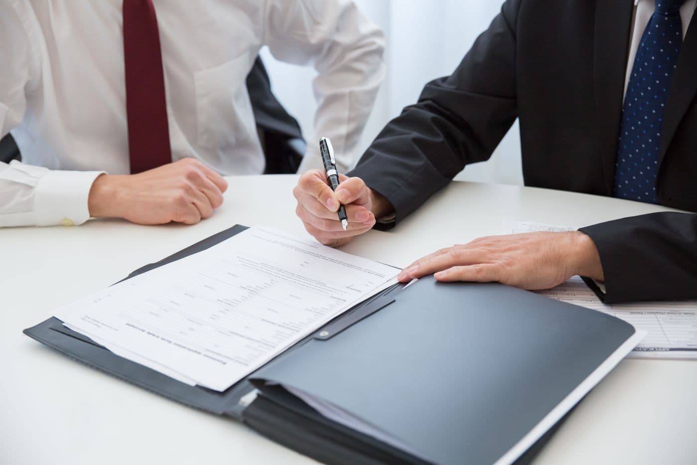 Signing documents in a leather folder at a meeting table — a company incorporation pack