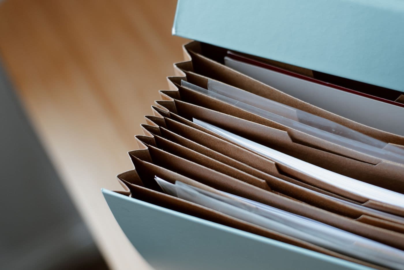 A folder organiser holding papers in kraft dividers on a wooden desk
