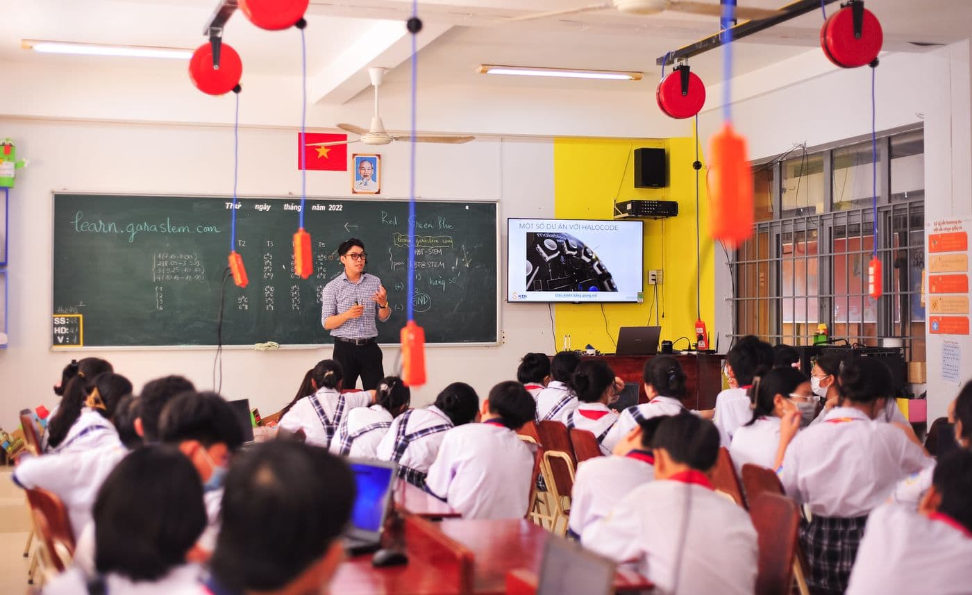 A classroom in a Vietnamese school: teacher at the board, pupils at their desks, the national flag on the wall