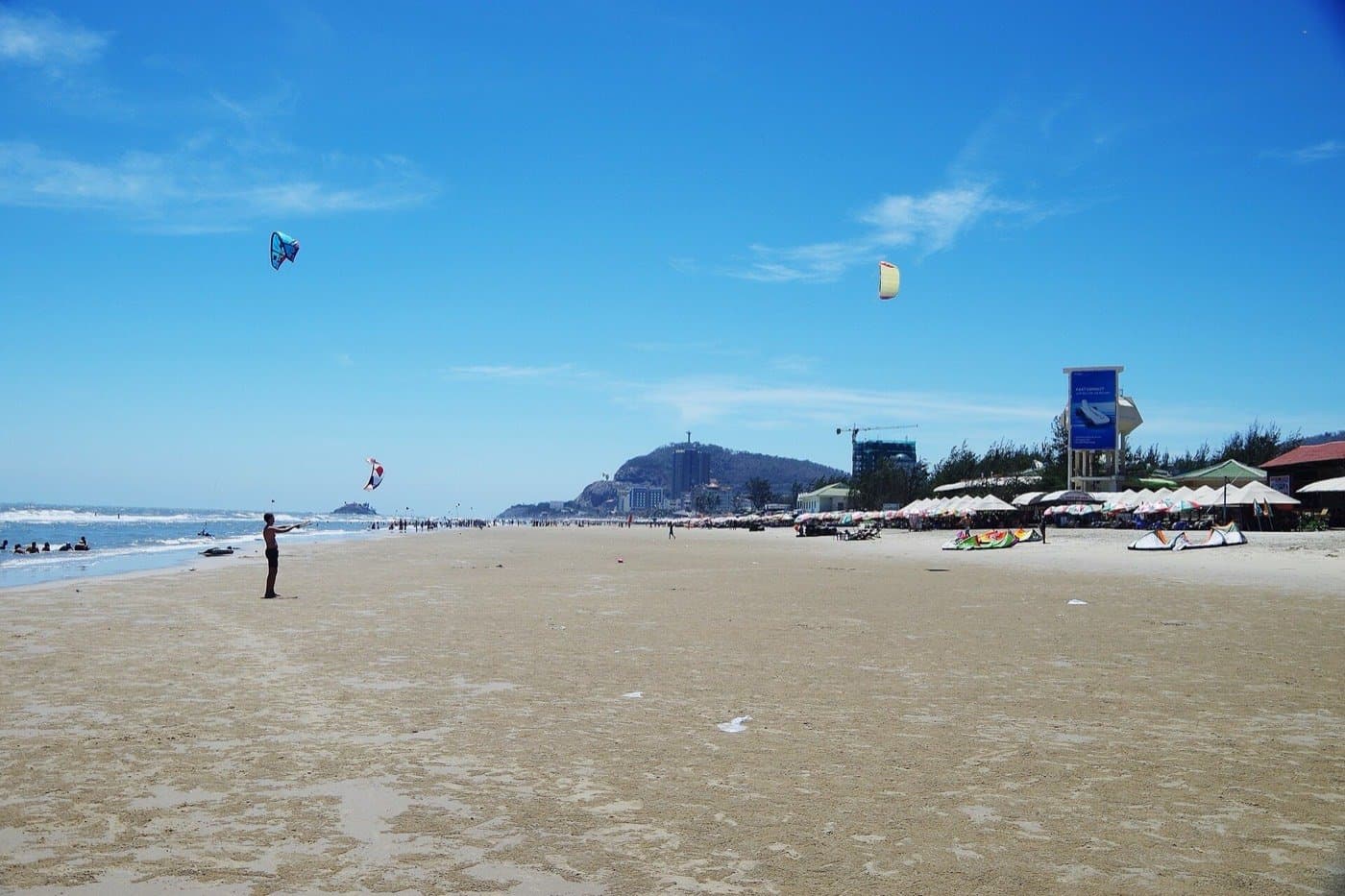 Пляж Back Beach в Вунгтау: зонтики, кайты в небе и Малая гора на горизонте